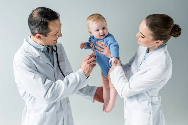 Pediatricians checking breath of beautiful little baby on grey — Stock Photo