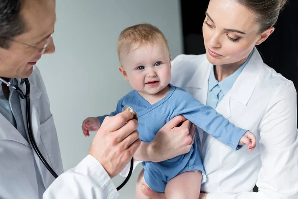 Nahaufnahme lächelnder Kinderärzte, die den Atem eines lächelnden kleinen Babys überprüfen — Stockfoto