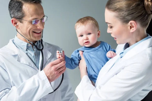 Pediatras revisando el aliento de un adorable bebé - foto de stock