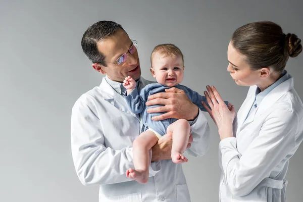Pediatras tratando de calmar pequeño bebé llorando en gris - foto de stock