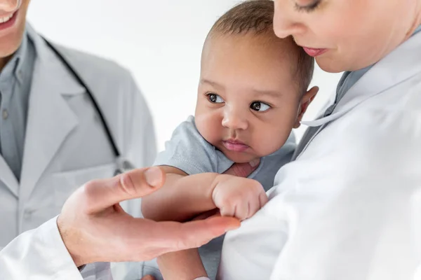 Tiro recortado de pediatras cuidando de pequeno bebê afro-americano — Fotografia de Stock