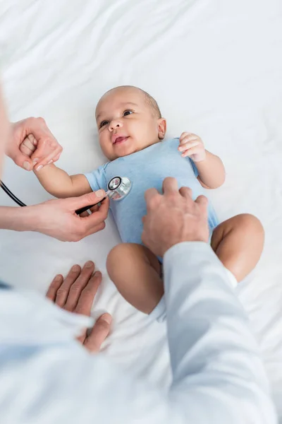 Recortado tiro de pediatras escuchando aliento de pequeño bebé con estetoscopio - foto de stock