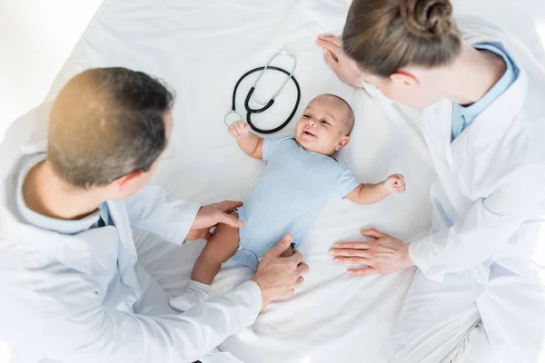 Visão de alto ângulo dos pediatras brincando com o bebê na cama — Fotografia de Stock
