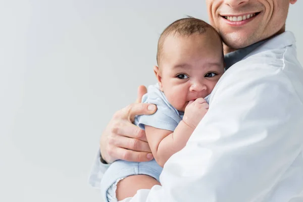 Recortado disparo de sonriente pediatra sosteniendo pequeño bebé aislado en blanco - foto de stock
