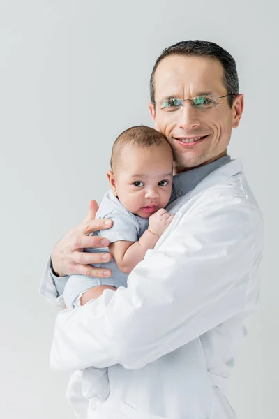 Smiling adult pediatrician holding little baby isolated on white — Stock Photo