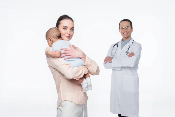 Mutter umarmt ihr Kind, während Kinderarzt isoliert auf weißem Hintergrund steht — Stockfoto