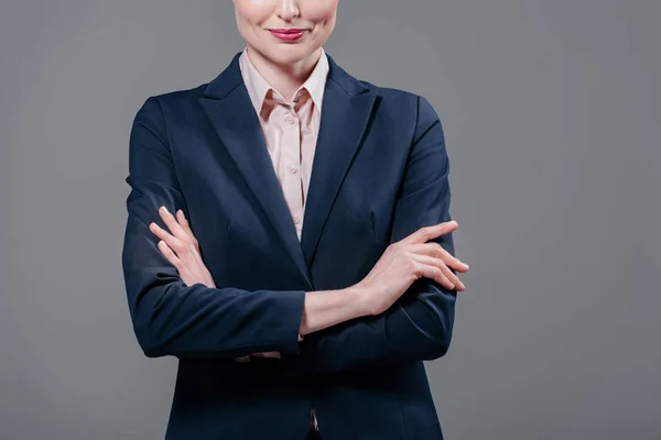 Обрізаний знімок усміхненої бізнес-леді з схрещеними руками ізольовано на сірому — стокове фото