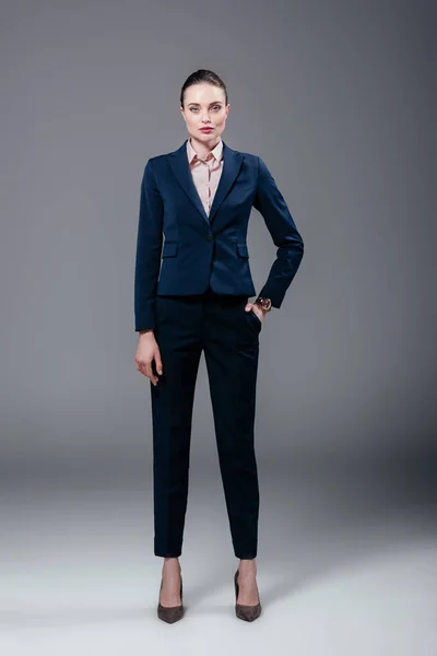 Attractive adult businesswoman in stylish suit on grey — Stock Photo