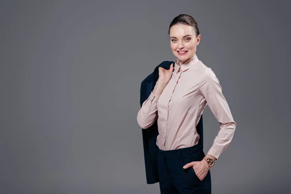 Smiling adult businesswoman with jacket on shoulder isolated on grey — Stock Photo