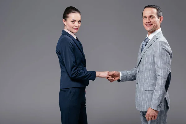 Colegas de negocios adultos estrechando las manos aislados en gris - foto de stock