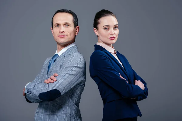 Adult business colleagues standing back to back and looking at camera isolated on grey — Stock Photo