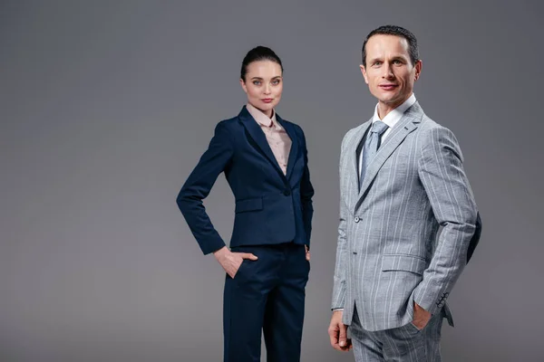 Confident adult business people looking at camera isolated on grey — Stock Photo