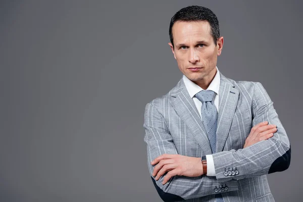 Handsome adult businessman with crossed arms looking at camera isolated on grey — Stock Photo