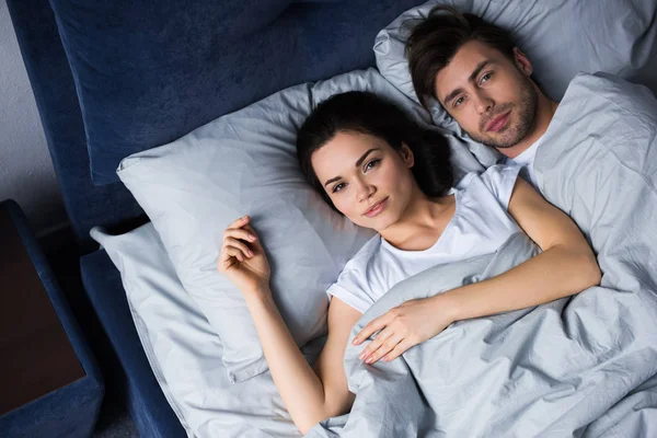 Молодой человек и женщина обнимаются, лежа в постели — стоковое фото