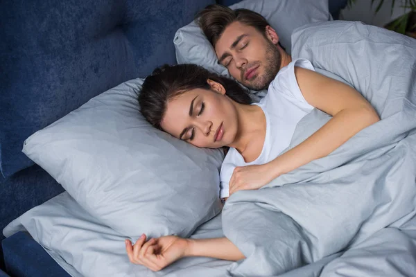 Jovem casal atraente abraçando enquanto dorme na cama — Fotografia de Stock