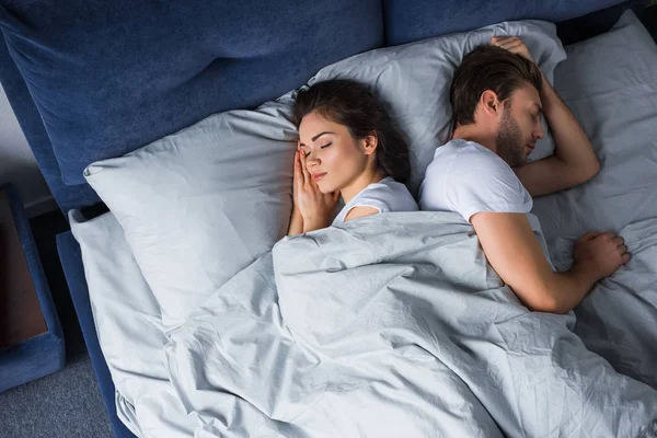 Pareja joven durmiendo en la cama en el dormitorio moderno - foto de stock