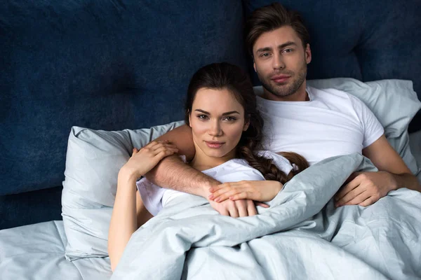 Young attractive couple hugging while lying in bed — Stock Photo