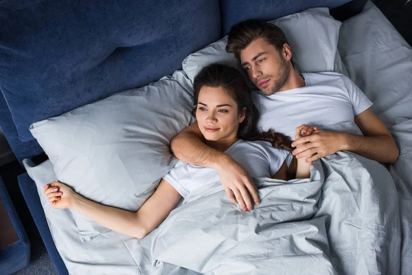 Sorrindo casal ternamente abraçando enquanto deitado na cama — Fotografia de Stock