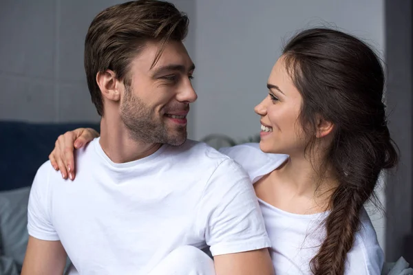 Junges attraktives Paar umarmt sich im Sitzen auf dem Bett — Stockfoto