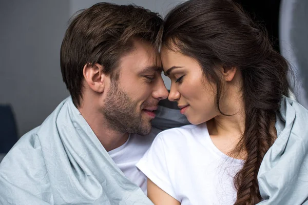 Joven pareja atractiva abrazándose debajo de la manta — Stock Photo