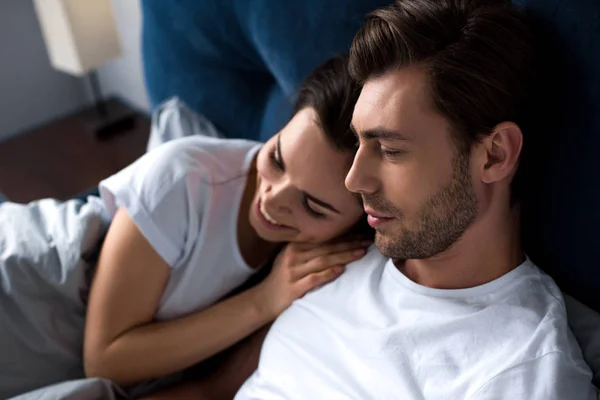 Smiling man and woman tenderly embracing while lying in bed — Stock Photo