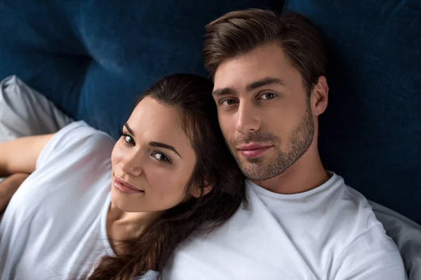 Smiling man and woman tenderly embracing in bed — Stock Photo