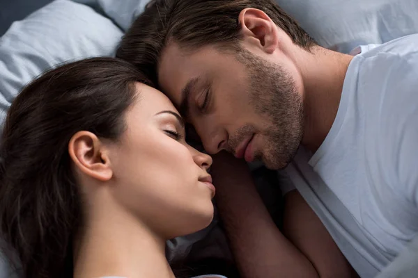Feliz joven pareja durmiendo en la cama - foto de stock