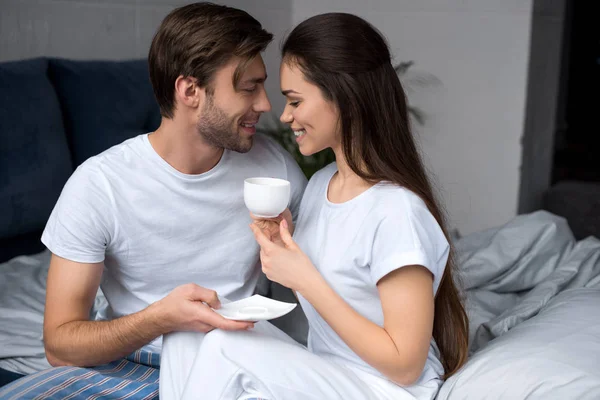 Glückliches Paar mit Kaffee in der Umarmung im Bett — Stockfoto