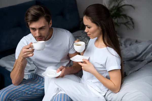 Jovem casal em loungewear beber café na cama — Fotografia de Stock