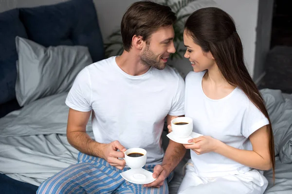 Lächelnde Frau und Mann trinken Kaffee im Bett — Stockfoto