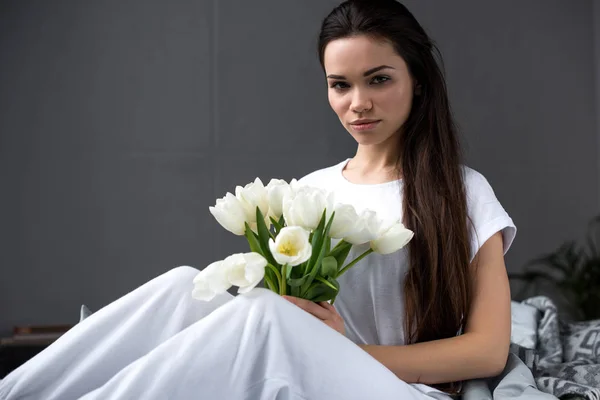 Beautiful young girl with white bouquet in bed — Stock Photo