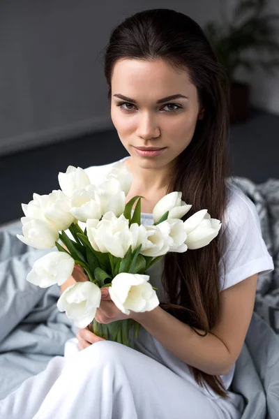 Mulher bonita segurando buquê de tulipas na cama — Fotografia de Stock