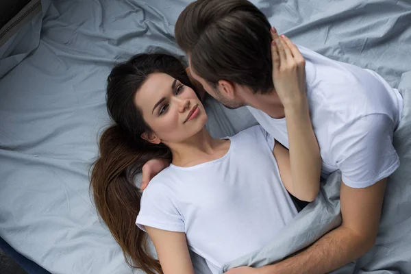 Frau umarmt und schaut ihren Mann im Bett an — Stockfoto