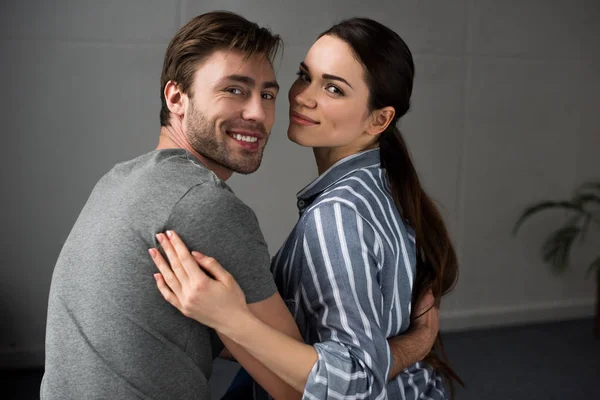 Smiling man and woman tenderly embracing in bedroom — Stock Photo