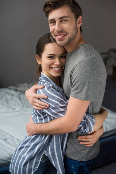 Lächelndes Paar, das sich im Schlafzimmer zärtlich umarmt — Stockfoto