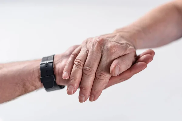 Cropped shot of senior man and rehabilitation therapist holding hands isolated on grey — Stock Photo