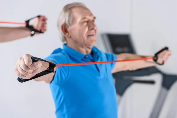 Selective focus of senior man exercising with rubber tape — Stock Photo