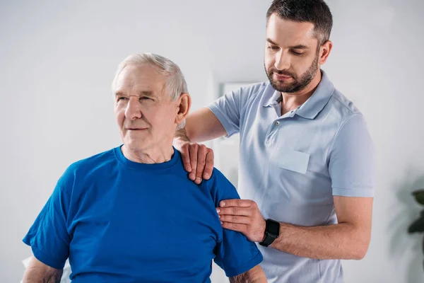 Retrato de fisioterapeuta haciendo masaje al hombre mayor - foto de stock
