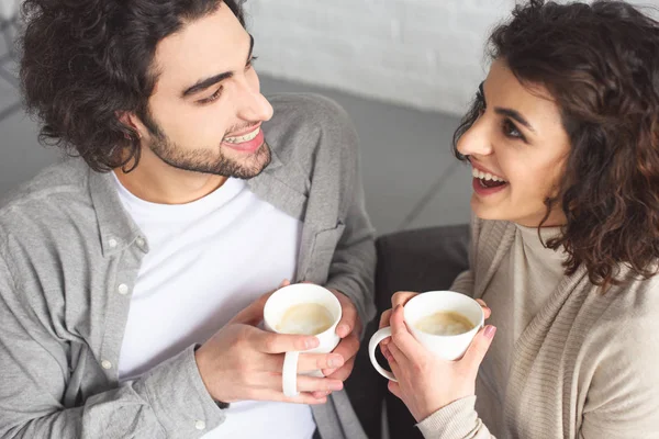 Vue grand angle de jeune couple riant boire du café à la maison — Photo de stock