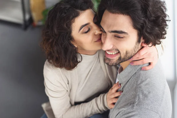 Freundin küsst lächelnden Freund zu Hause — Stockfoto