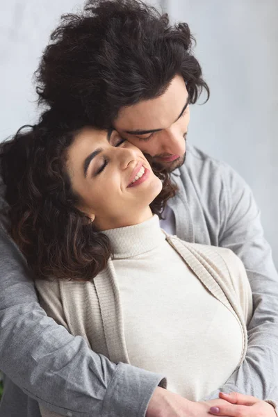 Feliz tierna joven pareja abrazándose en casa - foto de stock