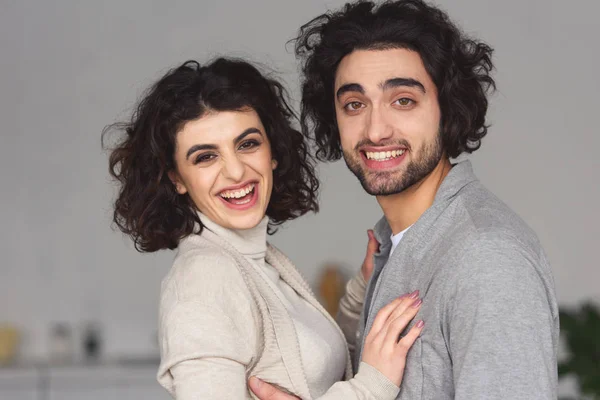 Sorridente giovane coppia abbracciare e guardando la fotocamera a casa — Foto stock