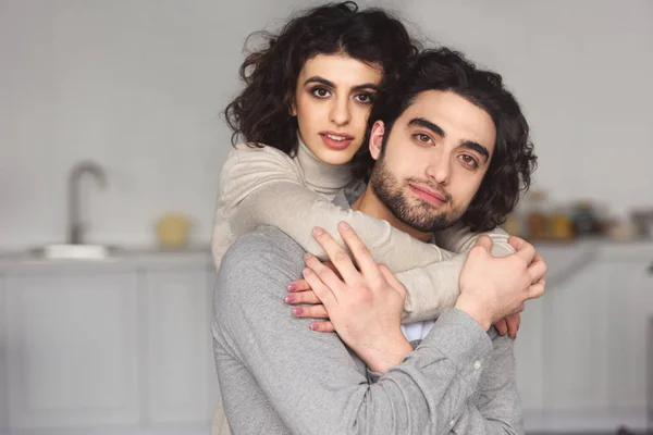 Girlfriend hugging boyfriend and they looking at camera at home — Stock Photo