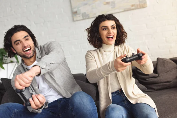 Riendo joven pareja jugando video juego en casa - foto de stock