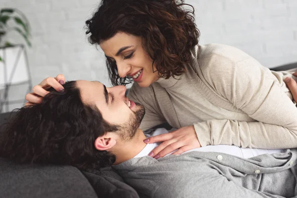 Young couple lying on sofa and looking at each other at home — Stock Photo