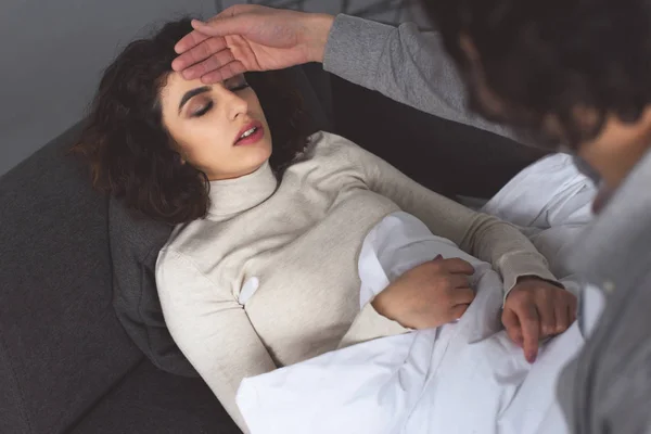 High angle view of boyfriend checking temperature of sick girlfriend and touching forehead at home — Stock Photo