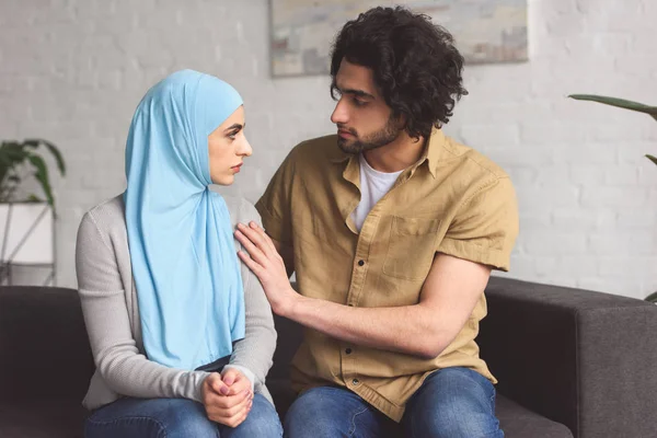 Muslim boyfriend hugging girlfriend in hijab in living room — Stock Photo