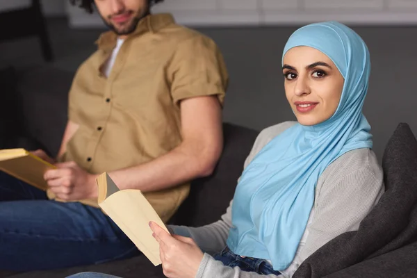 Imagen recortada de pareja musulmana sentada con libros en casa - foto de stock