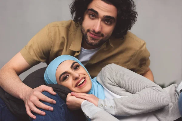 Sonriente pareja musulmana mirando a la cámara en casa - foto de stock