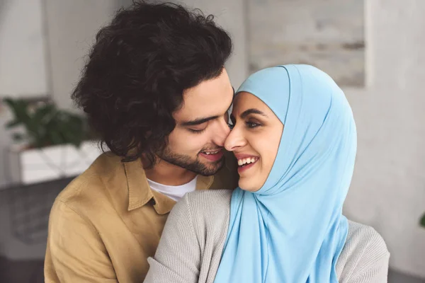 Lächelndes muslimisches Paar, das sich zu Hause umarmt und mit der Nase berührt — Stockfoto